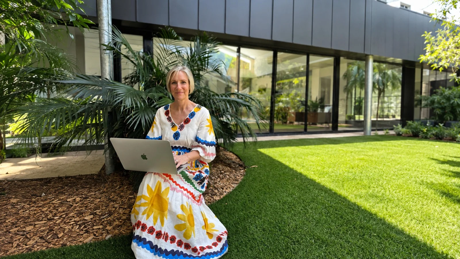 Amanda Ross, naturopath, working on a laptop in the garden at Health Hub Tweed Coast.
