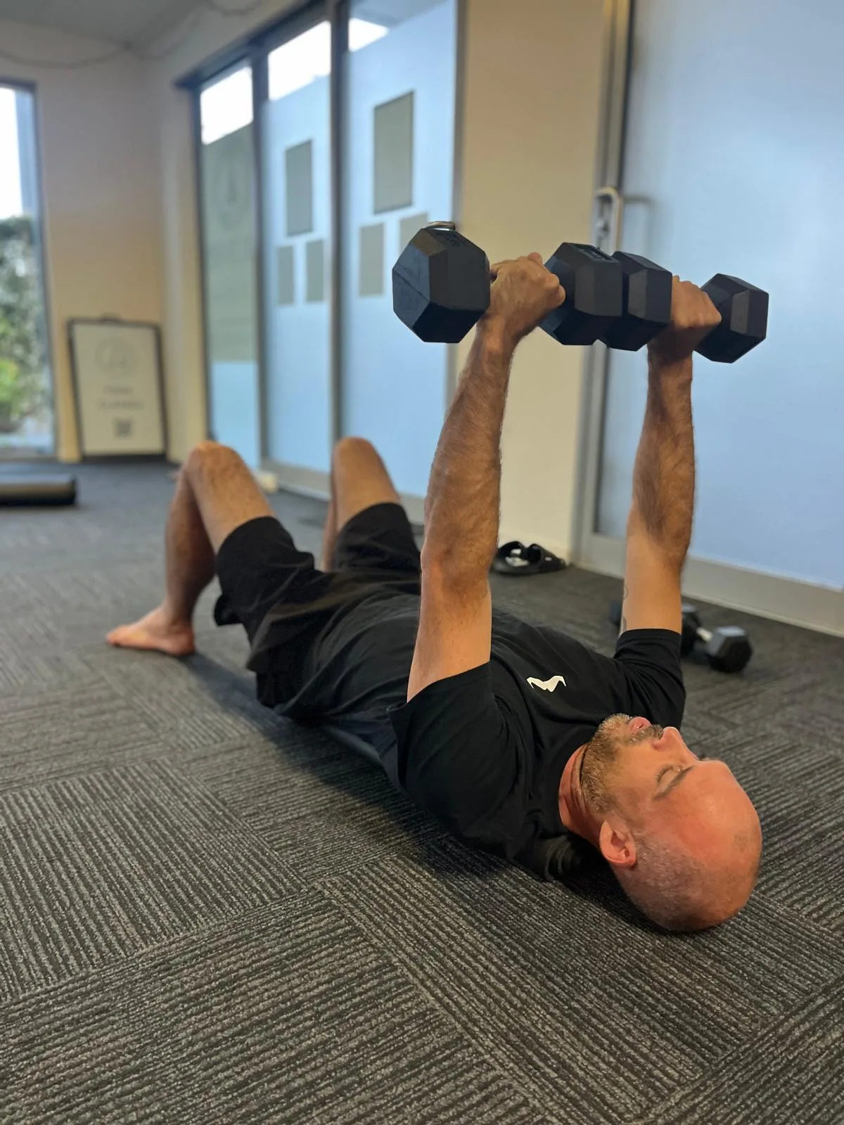 A dumbbell chest press on the studio floor during a Function & Flow session at Health Hub Tweed Coast.