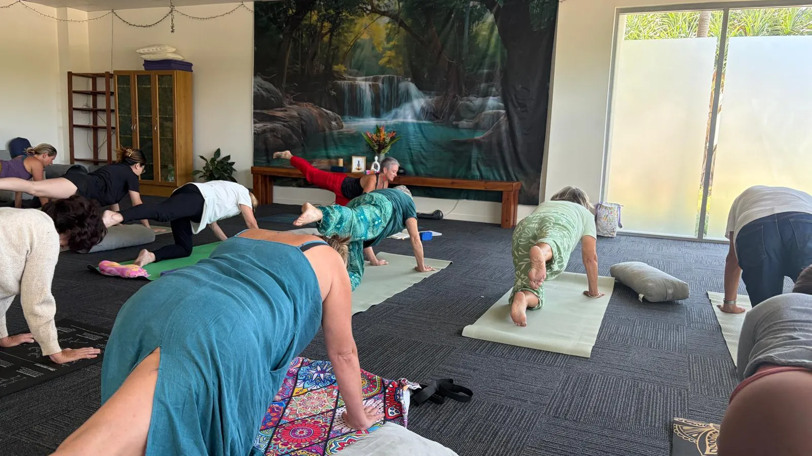 A guided yoga class in the studio at Health Hub Tweed Coast, moving through supported poses on mats and bolsters.